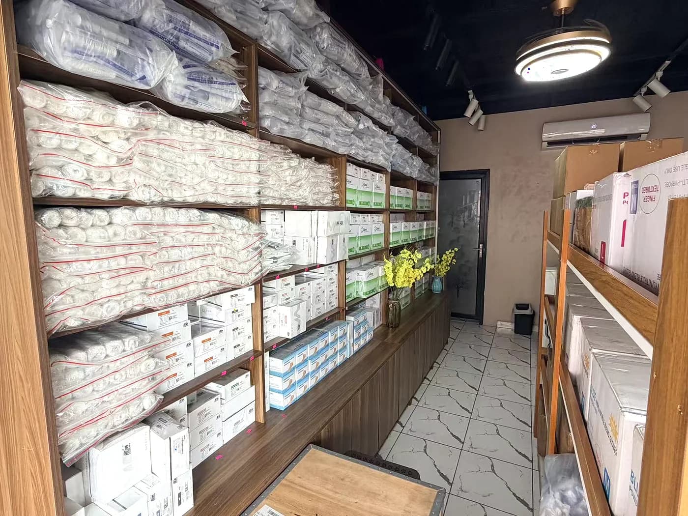 Shelving stacked with boxed medical consumables along the length of the store room